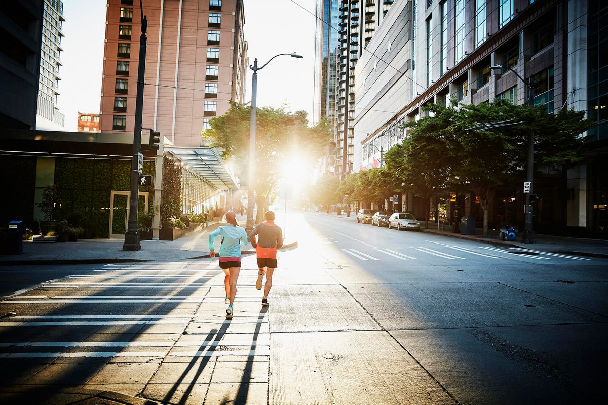 Two people run down the street in an urban area