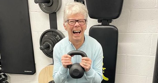 Ann Girling smiling in a gym, holding a kettle