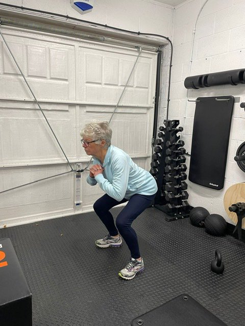 Ann Girling squatting in the gym